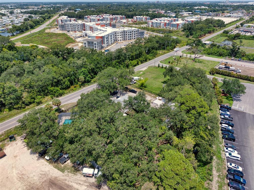An aerial view shows a wooded property with a house, pool, and adjacent parking lot — 4727 15TH STREET E, BRADENTON, FL