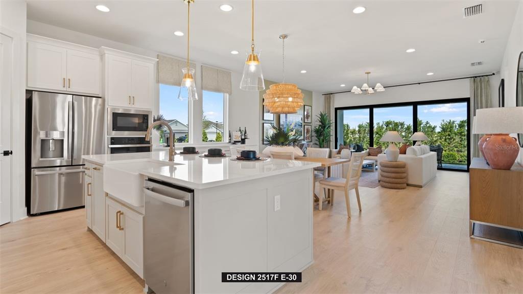A modern kitchen with white cabinets and a large island overlooks an open living area — 383 SUN CHASER DRIVE, NOKOMIS, FL