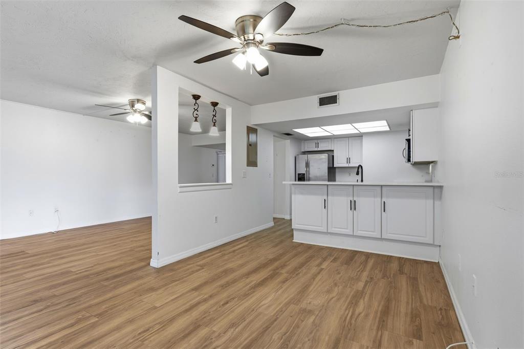 A kitchen with white cabinets and stainless steel appliances opens to a dining area — 6320 7TH AVENUE W, BRADENTON, FL