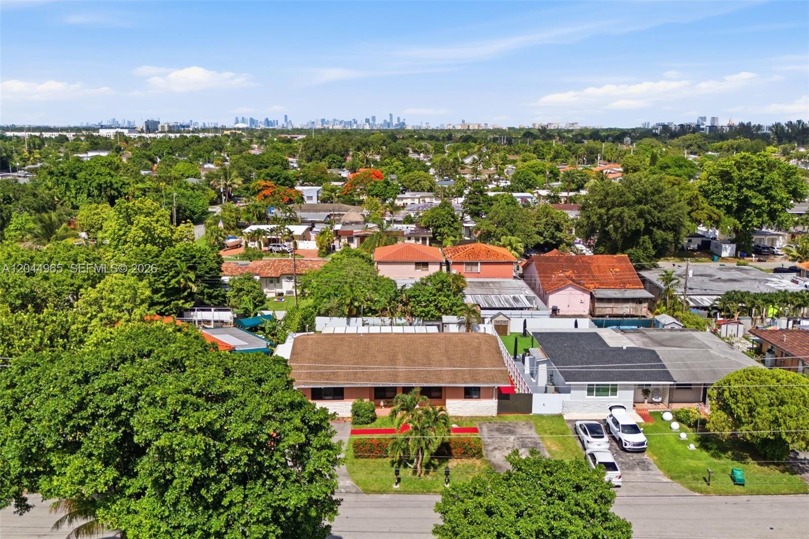 An aerial view shows a residential neighborhood with houses, trees, and a distant city skyline — 1421-1419 SW 76 ct, Miami FL 33144, MIAMI, FL