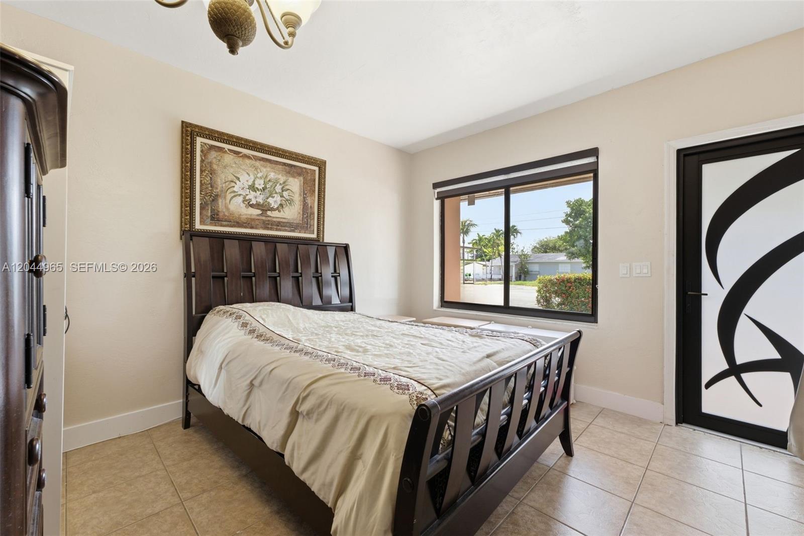 A bedroom features a dark wood bed frame, tile flooring, and a decorative glass door — 1421-1419 SW 76 ct, Miami FL 33144, MIAMI, FL