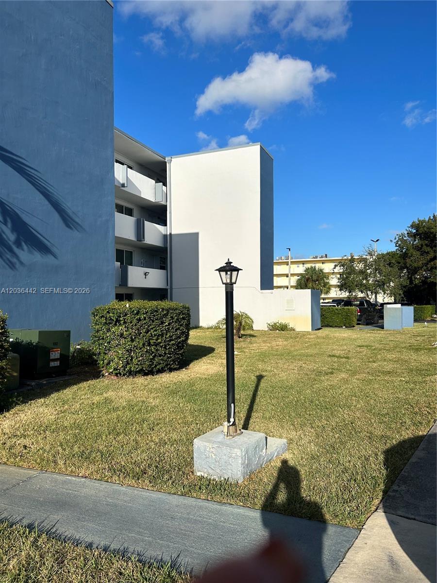 A view of a multi-story apartment building exterior with a lawn and a lamp post — 1101 NE 191st St # H401, Miami FL 33179, MIAMI, FL