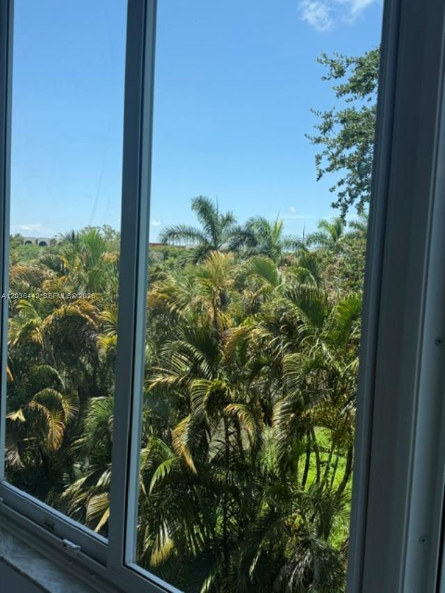 A view of lush palm trees and a clear blue sky through a window — 1101 NE 191st St # H401, Miami FL 33179, MIAMI, FL