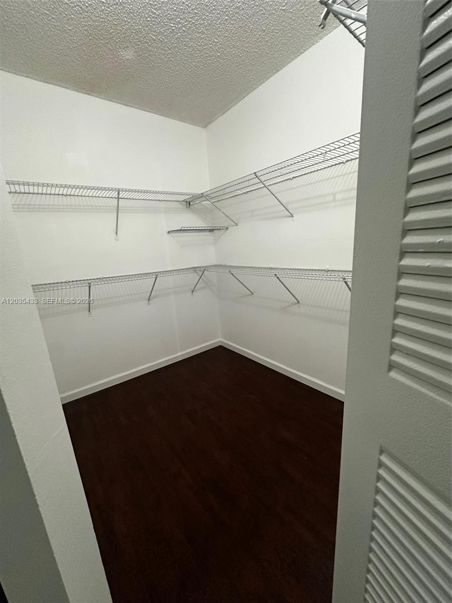 A walk-in closet features white wire shelving, white walls, and dark wood-look flooring — 18356 NW 68th Ave # K, Hialeah FL 33015, HIALEAH, FL