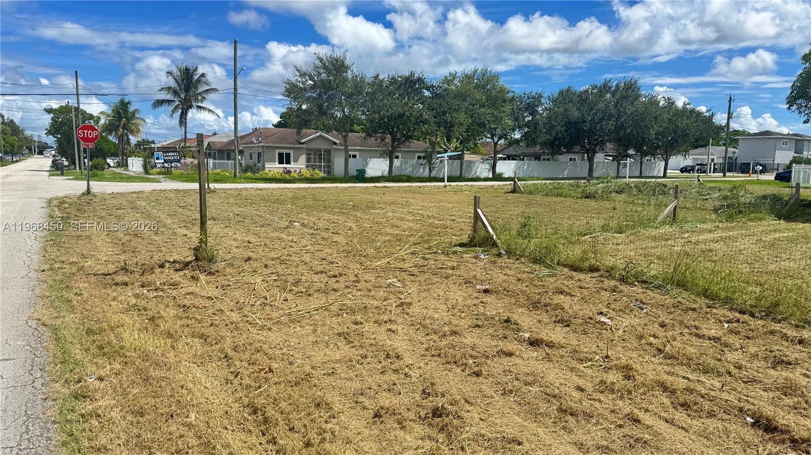 A vacant, grassy lot is enclosed by a wire fence with a street intersection nearby — 12208 SW 220 ST, Miami FL 33170, MIAMI, FL