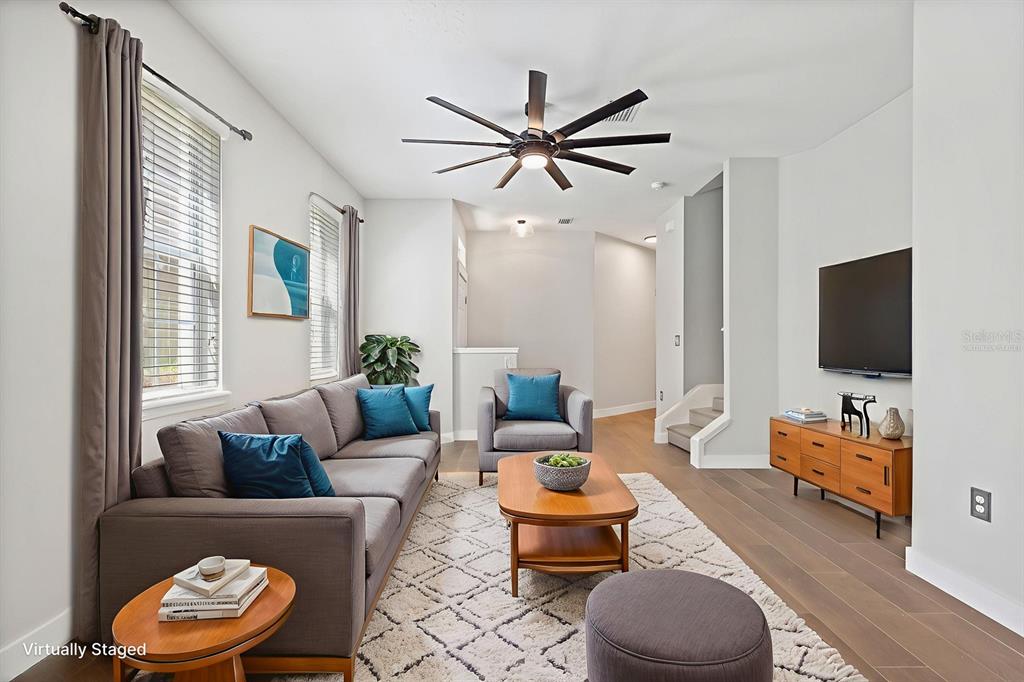 A living room features a gray sofa, armchair, wood coffee table, and a wall-mounted television — 9133 MOONLIT MEADOWS LOOP, RIVERVIEW, FL