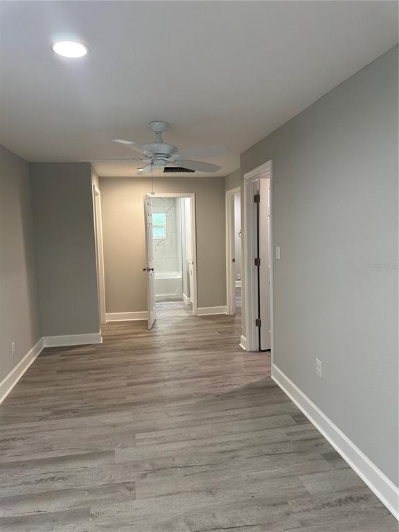 A room with light gray walls, wood-look flooring, a ceiling fan, and open doorways — 507 STONE STREET, WILDWOOD, FL