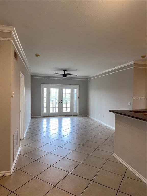 An interior view of a room with tiled floors, a ceiling fan, and glass doors — 4304 BAYSIDE VILLAGE DRIVE UNIT 303, TAMPA, FL
