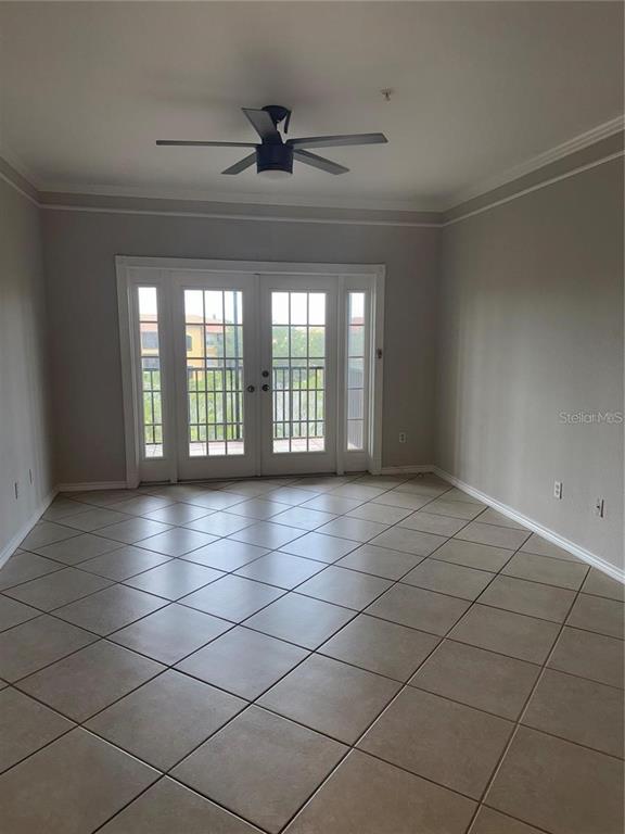 An empty room features beige tile flooring, a ceiling fan, and glass French doors — 4304 BAYSIDE VILLAGE DRIVE UNIT 303, TAMPA, FL