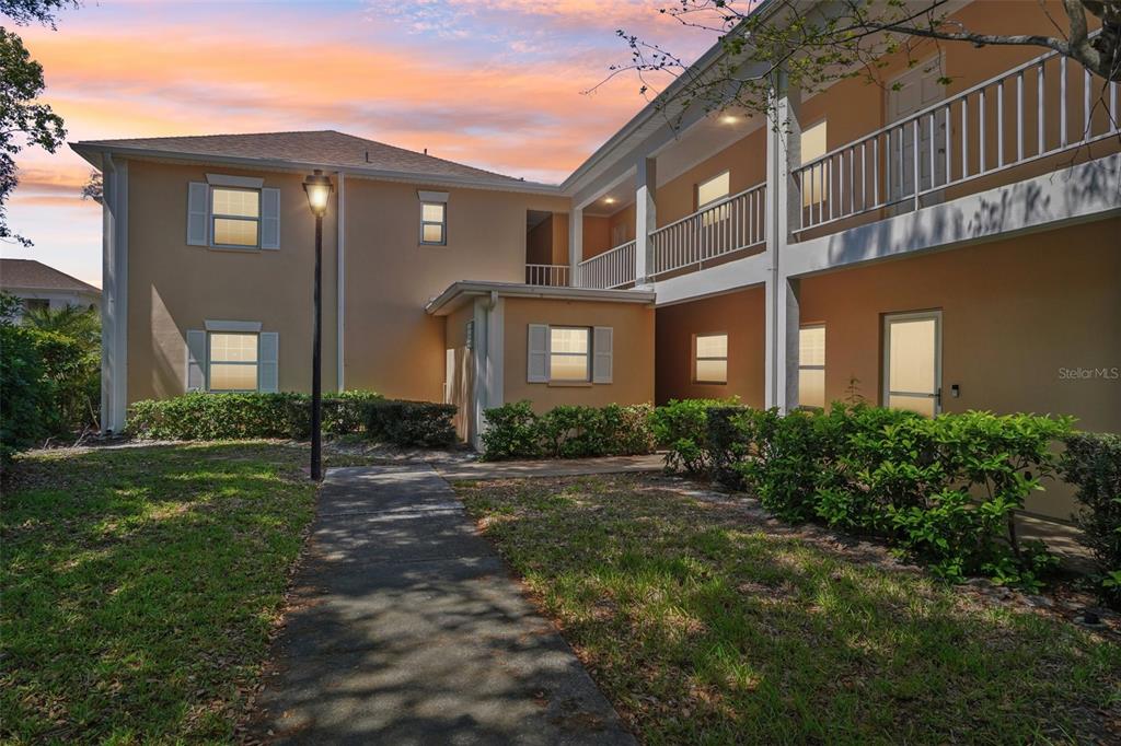 A two-story apartment building exterior features tan stucco walls, white railings, and a concrete walkway — 8300 BARDMOOR BOULEVARD UNIT 103, SEMINOLE, FL