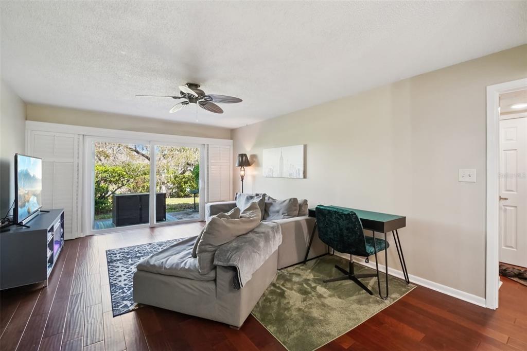 A living room features a sectional sofa, a desk, sliding glass doors, and hardwood floors — 8300 BARDMOOR BOULEVARD UNIT 103, SEMINOLE, FL