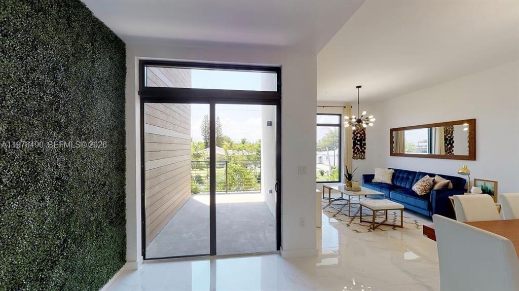 A living room features a blue sofa, white tile floors, and a sliding door to a balcony — 1501 N 17th Ave, Hollywood FL 33020, HOLLYWOOD, FL