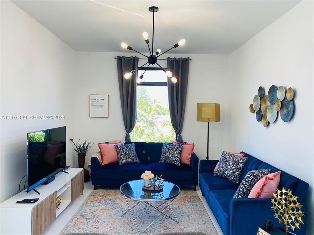 A living room features two blue velvet sofas, a glass coffee table, and a chandelier — 1501 N 17th Ave, Hollywood FL 33020, HOLLYWOOD, FL