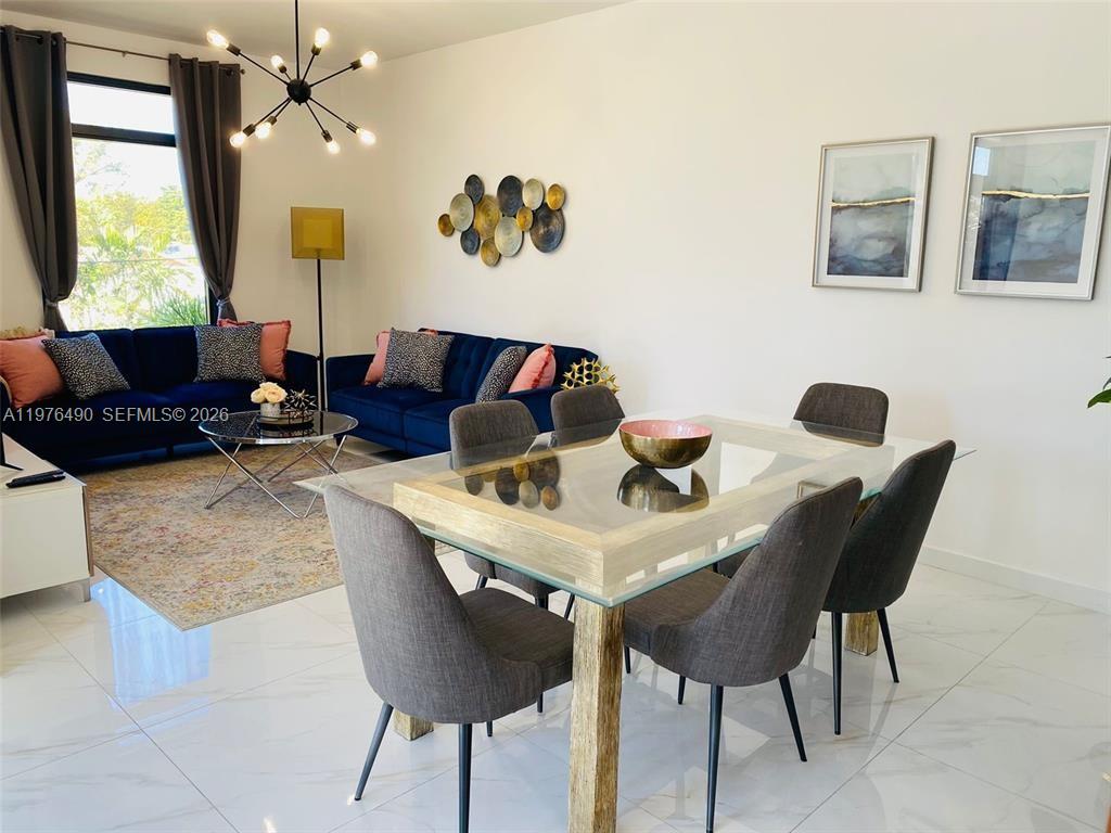 A dining area with a glass table and gray chairs sits before a blue sofa — 1501 N 17th Ave, Hollywood FL 33020, HOLLYWOOD, FL