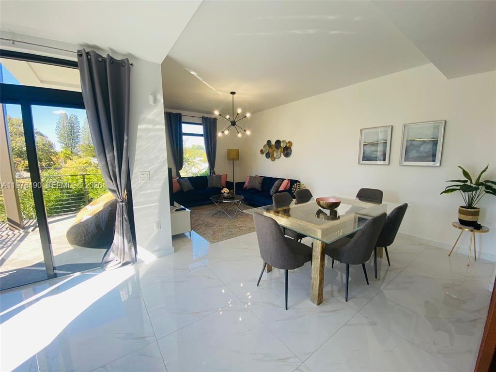 A bright open-concept living and dining area features white marble floors and a glass table — 1501 N 17th Ave, Hollywood FL 33020, HOLLYWOOD, FL