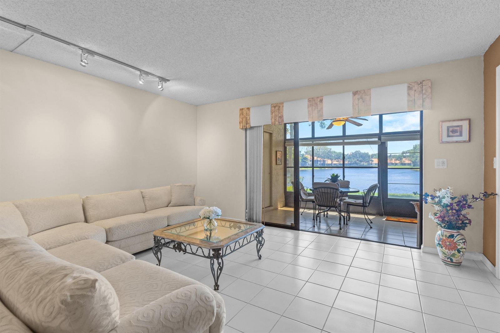 A living room with white tile floors, a sectional sofa, and a sliding door to a patio — 9700 Pavarotti Terrace # 102, Boynton Beach FL 33437, BOYNTON BEACH, FL