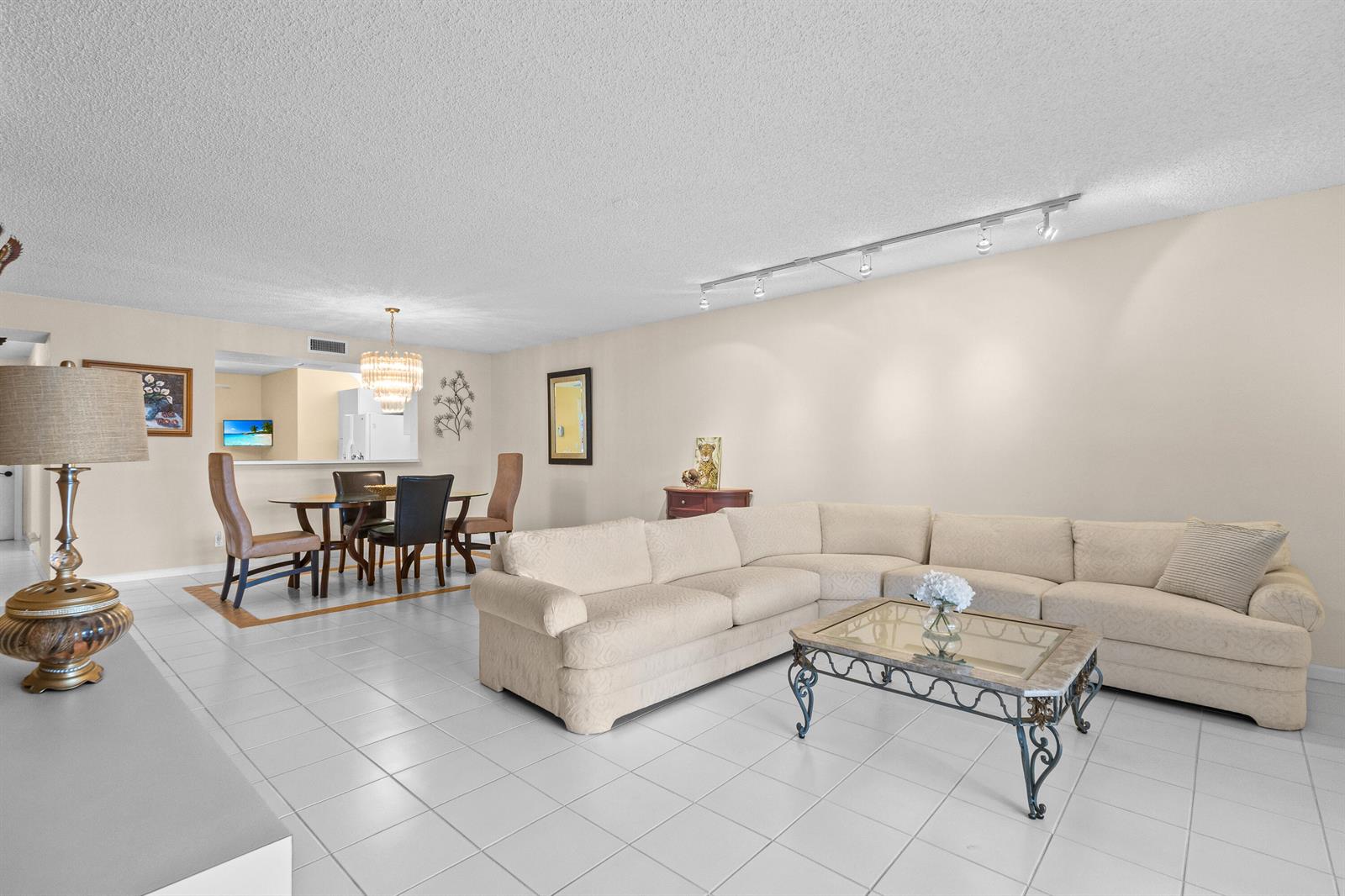 A living room with white tile floors, a large sectional sofa, and an adjacent dining area — 9700 Pavarotti Terrace # 102, Boynton Beach FL 33437, BOYNTON BEACH, FL