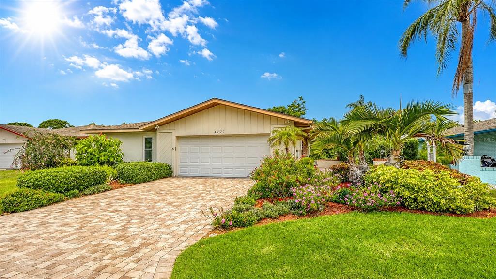 A single-story house with a paved driveway, a two-car garage, and lush landscaping — 4777 RINGWOOD MEADOW, SARASOTA, FL