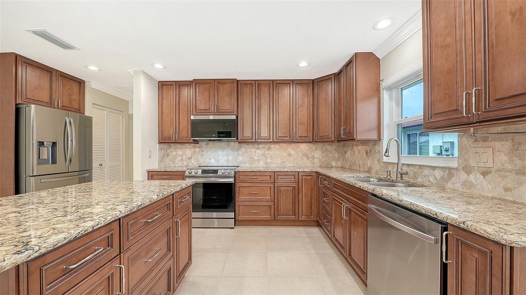 A kitchen features wood cabinets, granite countertops, stainless steel appliances, and a central island — 4777 RINGWOOD MEADOW, SARASOTA, FL