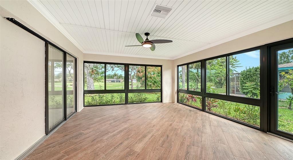 A sunroom with wood-look tile flooring, a ceiling fan, and large windows overlooking a yard — 4777 RINGWOOD MEADOW, SARASOTA, FL