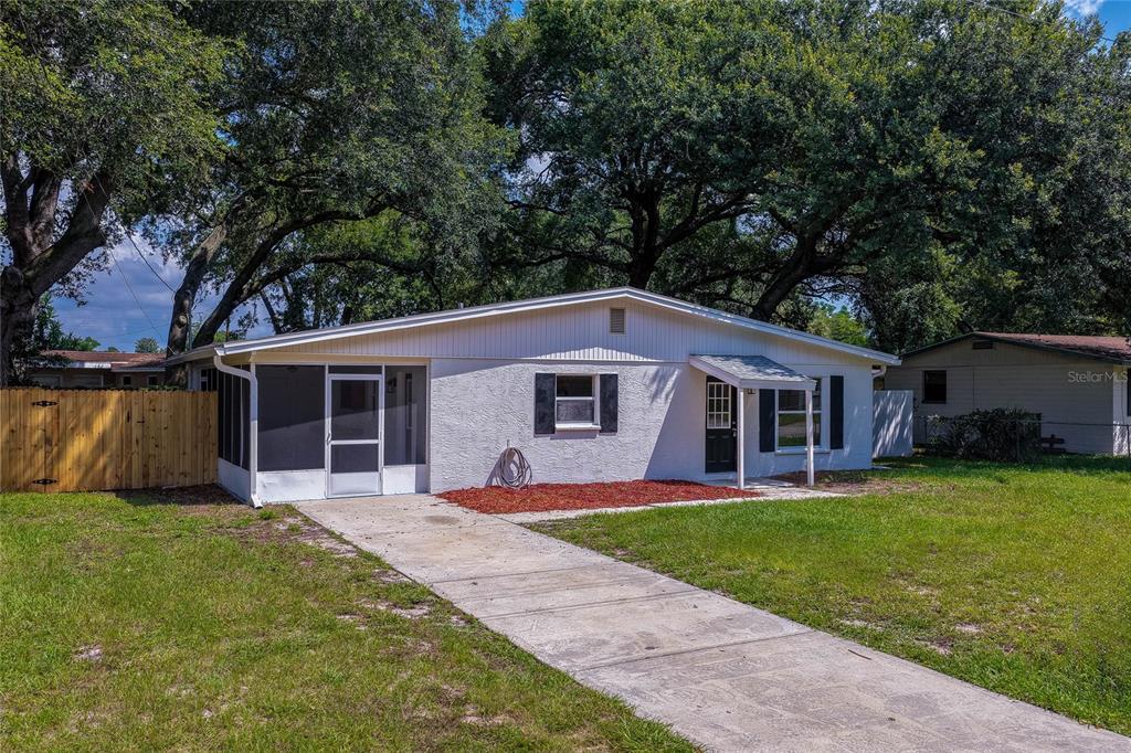 A single-story white house with a screened-in porch and a concrete driveway — 1220 LEON LANE, DAYTONA BEACH, FL