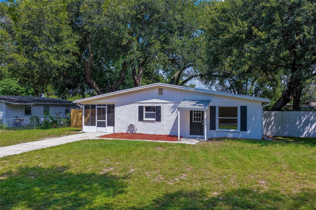 A white, single-story house with a front porch, black shutters, and a large grassy yard — 1220 LEON LANE, DAYTONA BEACH, FL