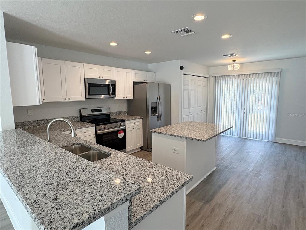 A kitchen with white cabinets, granite countertops, stainless steel appliances, and a center island — 319 PEARL STREET, LAKE WALES, FL