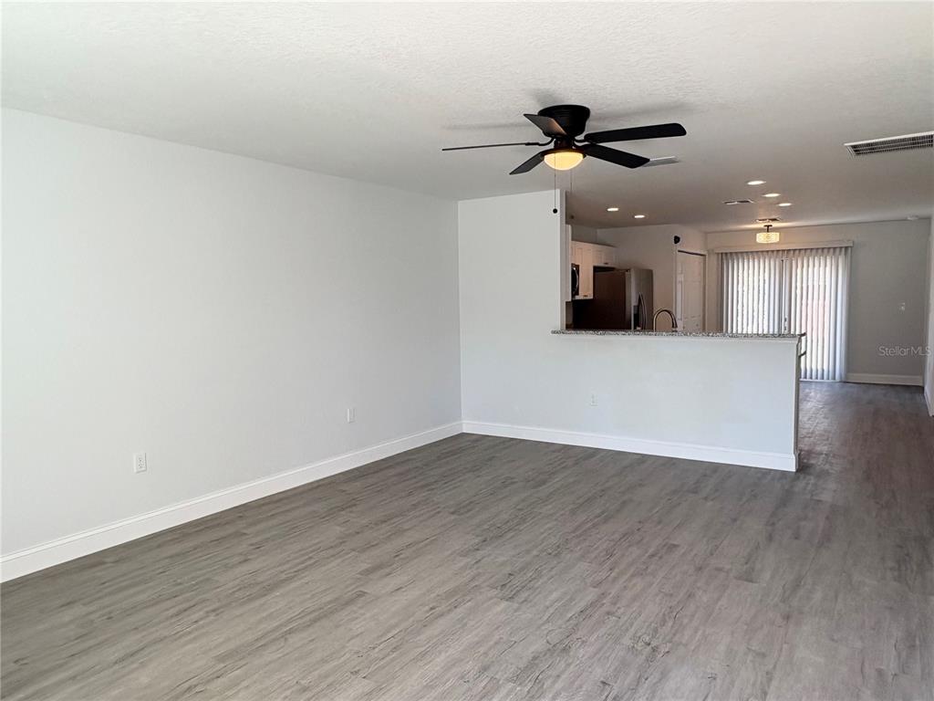 A living room with gray wood-look flooring opens to a kitchen with a breakfast bar — 319 PEARL STREET, LAKE WALES, FL