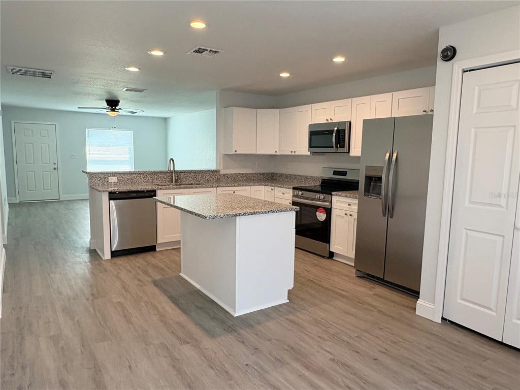 A kitchen features white cabinets, granite countertops, stainless steel appliances, and a central island — 319 PEARL STREET, LAKE WALES, FL