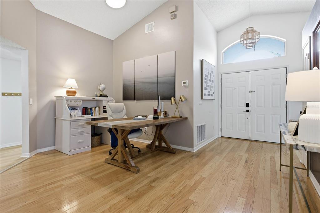 A home office with a wooden desk, white hutch, and hardwood floors near an entryway — 13917 TALLOWRIDGE COURT, ORLANDO, FL