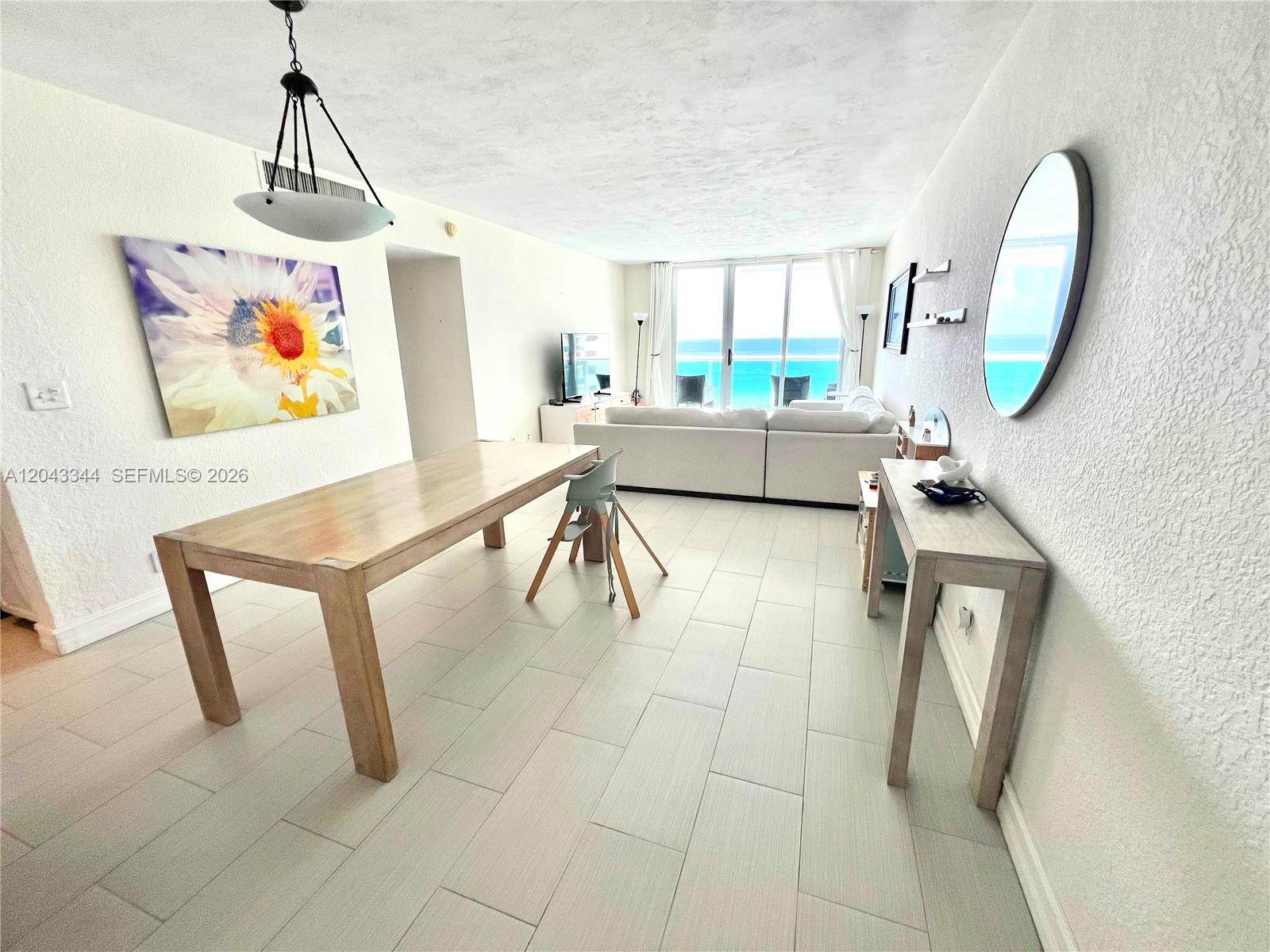 This open-concept living and dining area features light tile flooring and a view of the ocean — 3801 S Ocean Dr # 11M, Hollywood FL 33019, HOLLYWOOD, FL