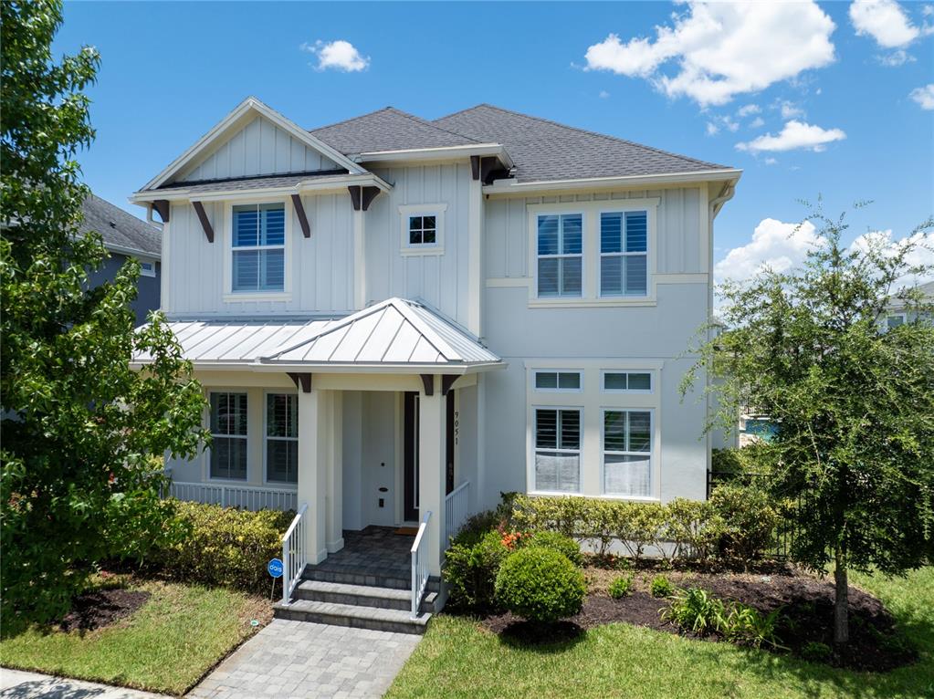 A two-story house with white siding, a metal-roofed porch, and a paved walkway — 9051 SPERRY STREET, ORLANDO, FL