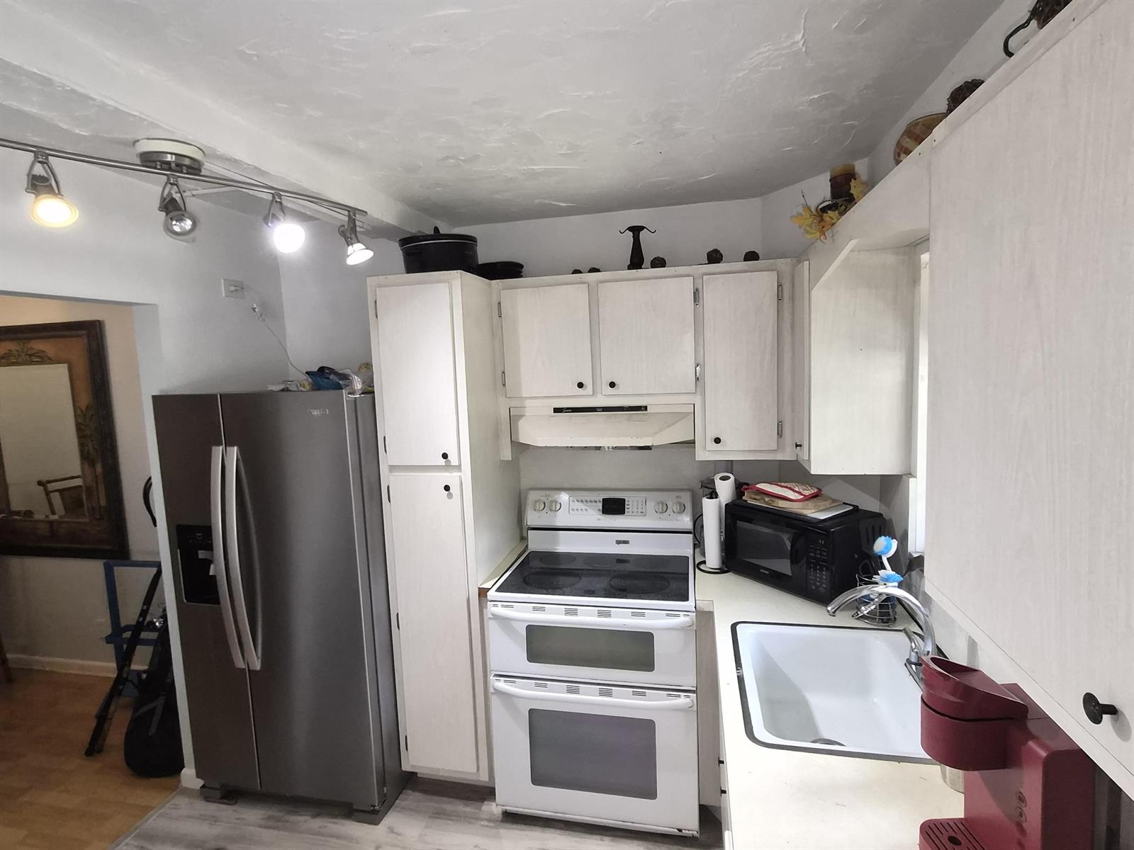 A kitchen features white cabinets, a stainless steel refrigerator, a white stove, and a sink — 100 Royal Palm Way # 2040, Boca Raton FL 33432, BOCA RATON, FL