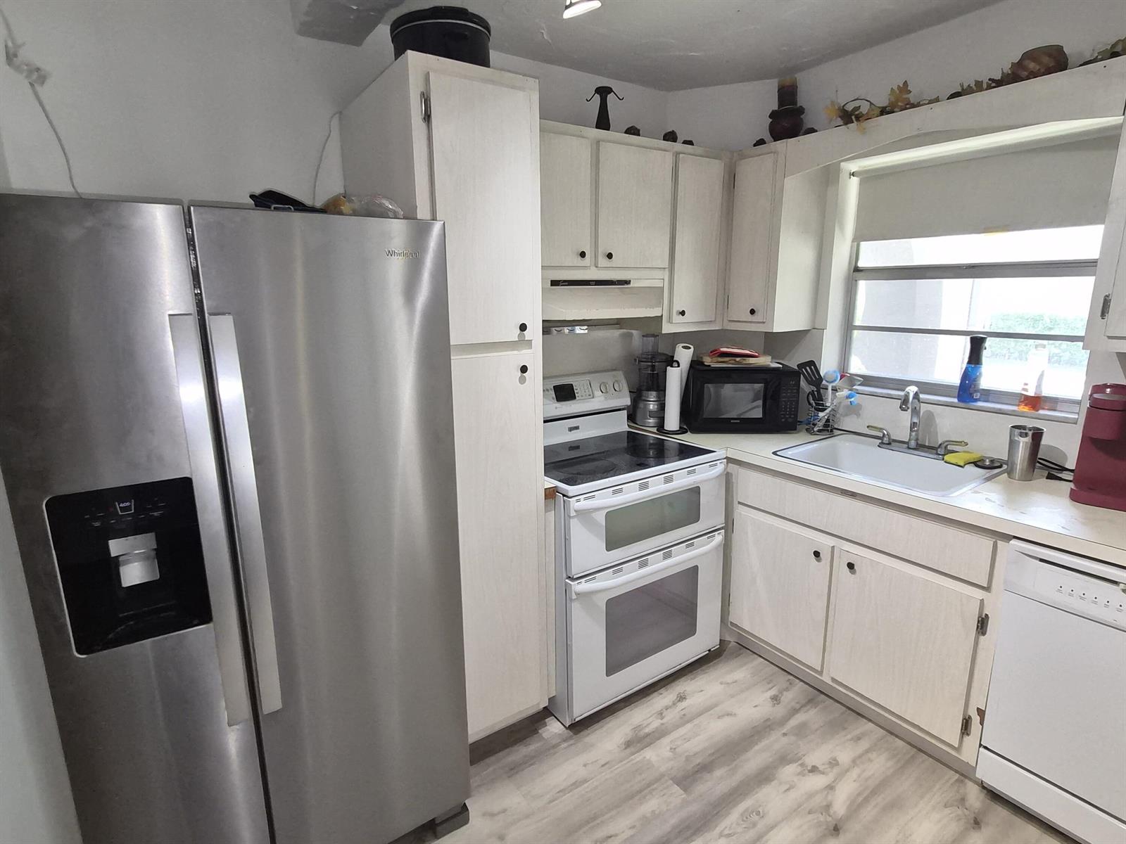 A kitchen features white cabinets, stainless steel appliances, a double oven, and wood-look flooring — 100 Royal Palm Way # 2040, Boca Raton FL 33432, BOCA RATON, FL