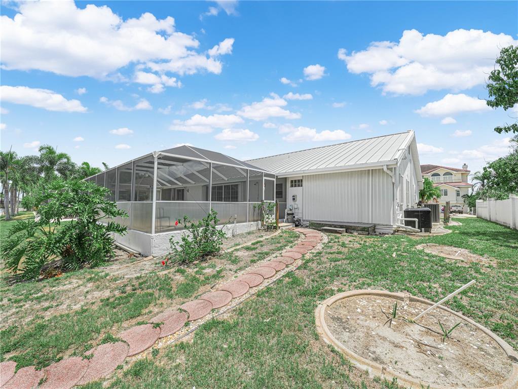 A backyard view of a house with a screened-in porch and a stone walkway — 262 GEORGE ROAD SE, PORT CHARLOTTE, FL