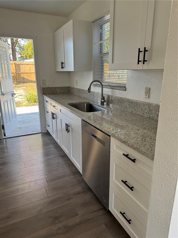 A kitchen features white cabinets, granite countertops, a stainless steel dishwasher, and wood-look flooring — 425 HOLLYHOCK LANE, SPRING HILL, FL