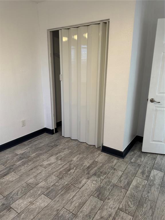 A room features gray wood-look flooring, white walls, a folding closet door, and a doorway — 425 HOLLYHOCK LANE, SPRING HILL, FL