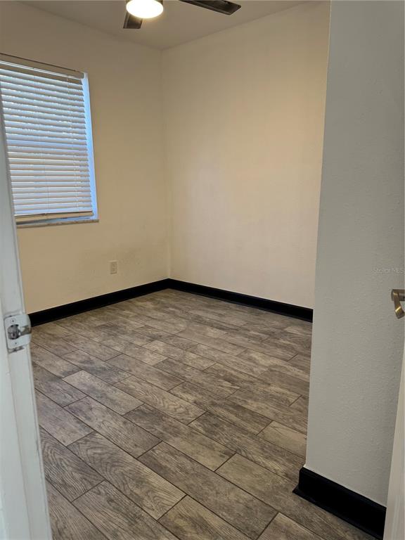 An empty room features wood-look tile flooring, white walls, and dark baseboards — 425 HOLLYHOCK LANE, SPRING HILL, FL