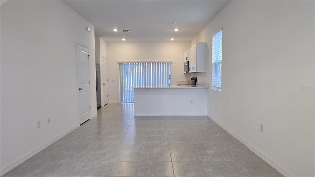 An open-concept kitchen with white cabinets and a breakfast bar overlooks a tiled dining area — 2970 SKYLINE LOOP, POINCIANA, FL