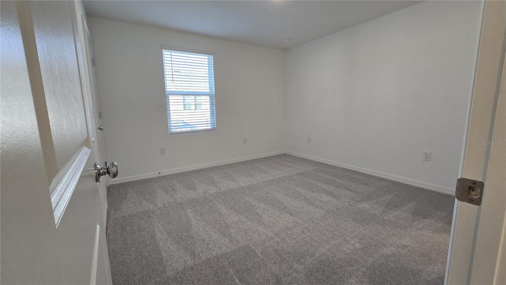 An empty bedroom features white walls, gray carpeting, and a single window with blinds — 2970 SKYLINE LOOP, POINCIANA, FL