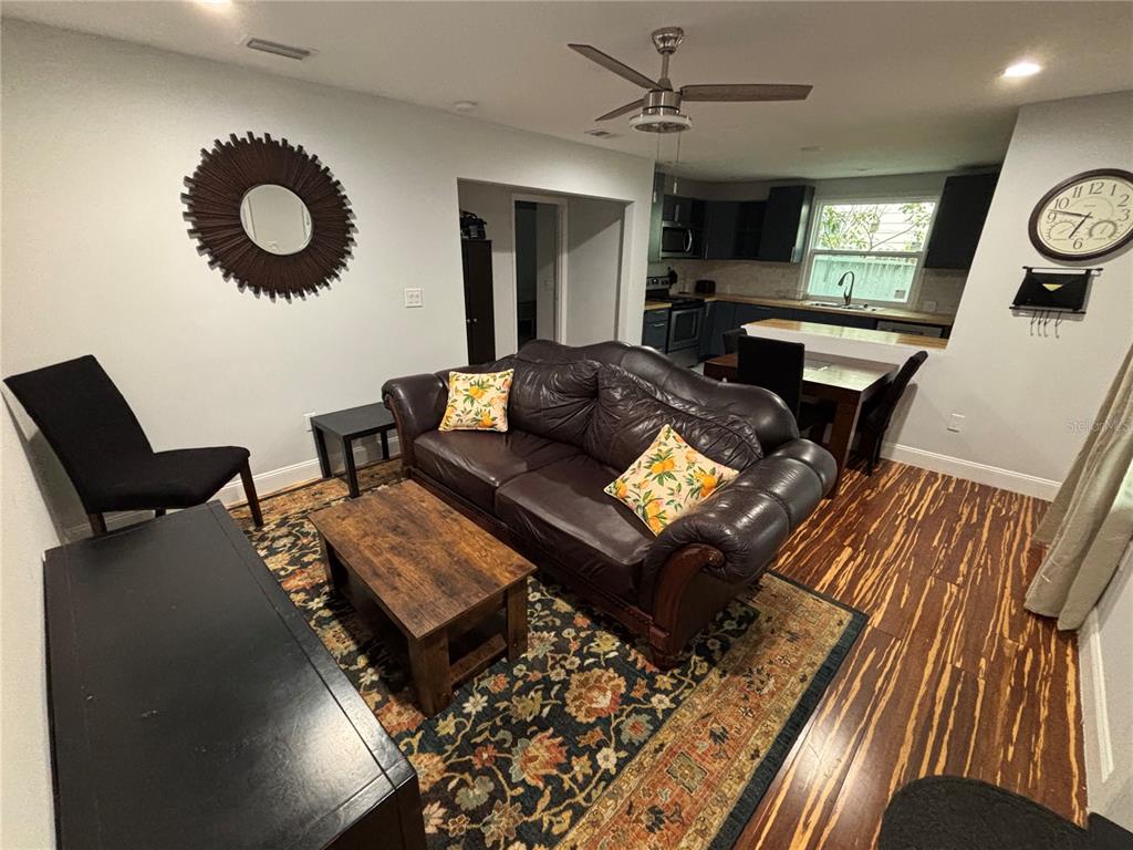 A living room with a leather sofa, patterned rug, and an open kitchen in the background — 1319 S MICHIGAN AVENUE, CLEARWATER, FL