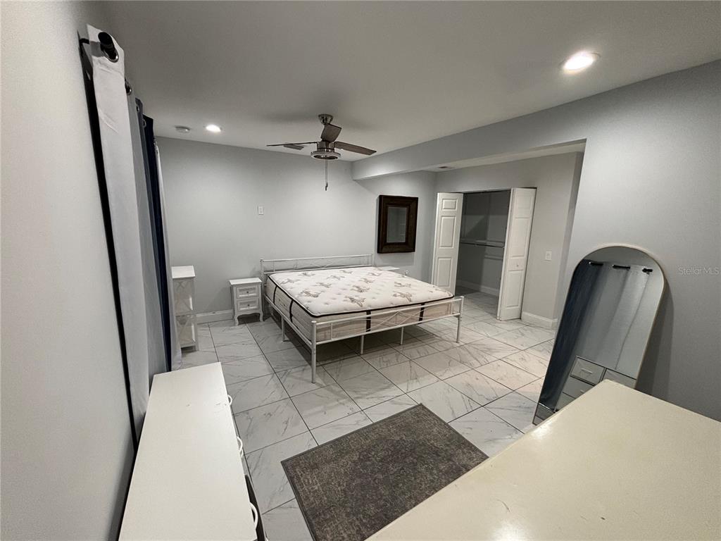 A bedroom features a white metal bed frame, tile flooring, and a walk-in closet — 1319 S MICHIGAN AVENUE, CLEARWATER, FL