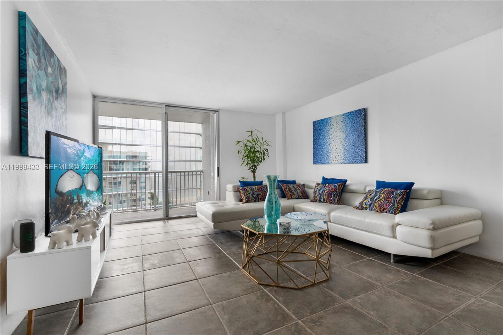 A living room features a white sectional sofa, a geometric coffee table, and tile flooring — 150 SE 25th Rd # 12B, Miami FL 33129, MIAMI, FL