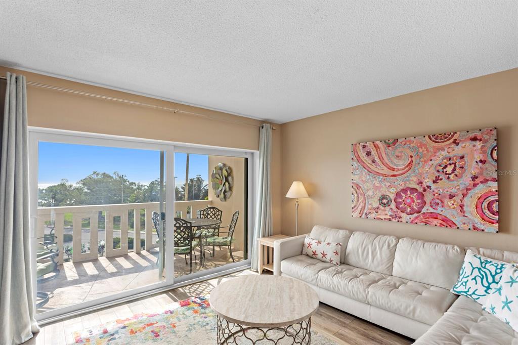 A living room features a white sectional sofa, a round coffee table, and a sliding door — 1200 N SHORE DRIVE NE UNIT 407, ST PETERSBURG, FL