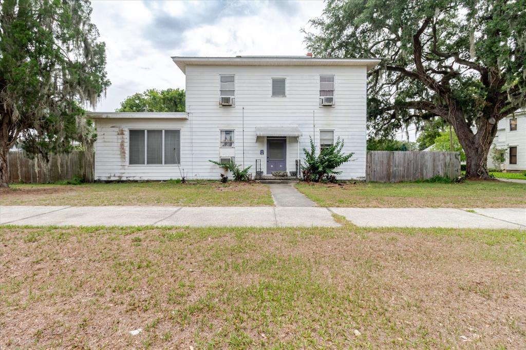 A two-story white house with a flat roof, a front entrance, and a large tree — 605 S JACKSON AVENUE, BARTOW, FL