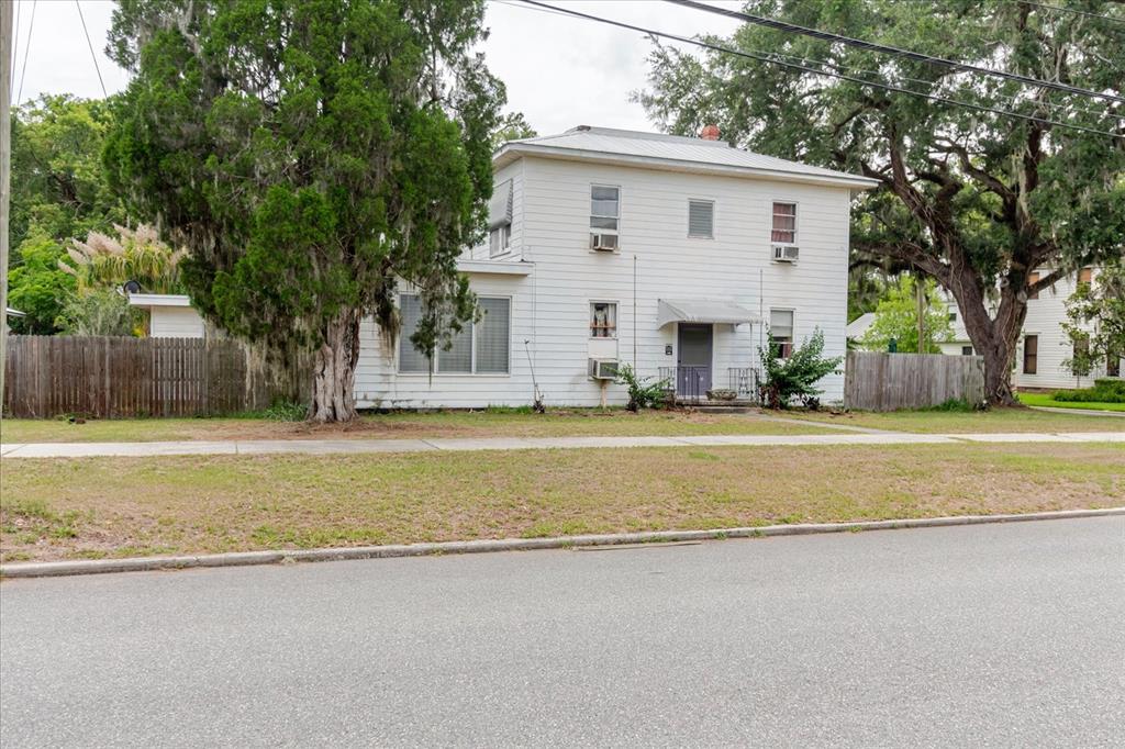A two-story white house with a metal roof sits behind a lawn and sidewalk — 605 S JACKSON AVENUE, BARTOW, FL