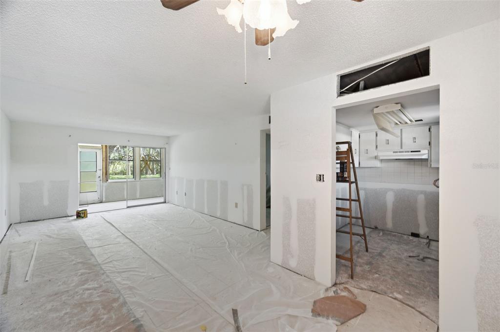 An interior view of a room under renovation with exposed drywall and a kitchen doorway — 4829 ONYX LANE UNIT 102, NEW PORT RICHEY, FL