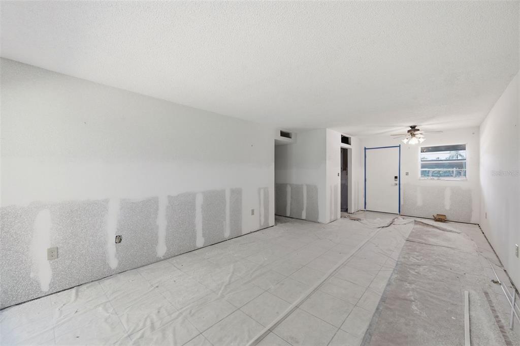 An unfinished room with white walls, tiled flooring, and a ceiling fan near the entrance — 4829 ONYX LANE UNIT 102, NEW PORT RICHEY, FL