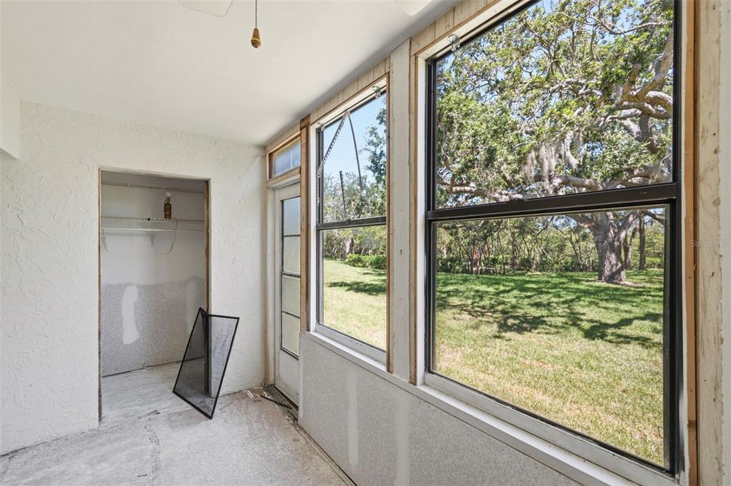 An unfinished sunroom with large windows, a closet, and a view of a grassy yard — 4829 ONYX LANE UNIT 102, NEW PORT RICHEY, FL
