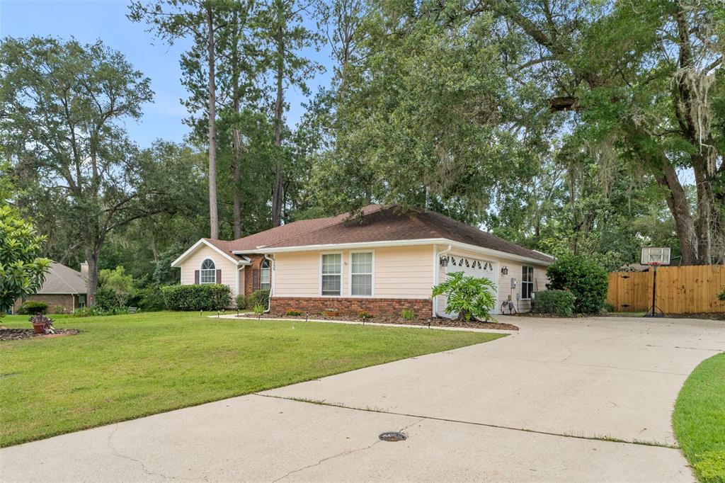 A single-story house with light siding, a brick base, and a concrete driveway — 9239 NW 16TH PLACE, GAINESVILLE, FL